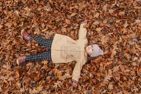 Photo for Girl lies in fallen leaves - Royalty Free Image
