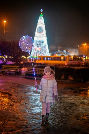 Photo for Girl against the backdrop of the citys large New Year tree in the evening - Royalty Free Image