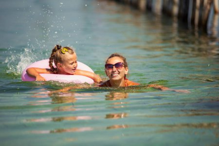 Photo for Mother and daughter swim in the sea near the shore - Royalty Free Image
