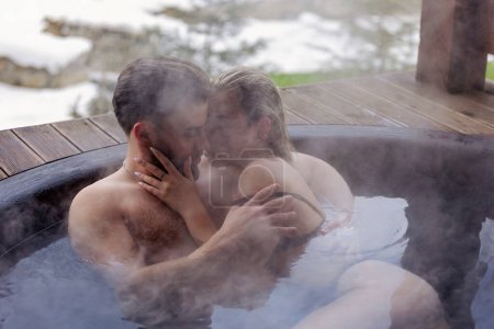 Photo for Young couple hugging while sitting in a big tub of water - Royalty Free Image