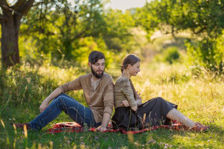 Photo for Couple sitting in nature with their backs to each other - Royalty Free Image