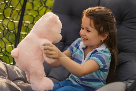 Photo for Girl playing with her teddy bear being in nature - Royalty Free Image