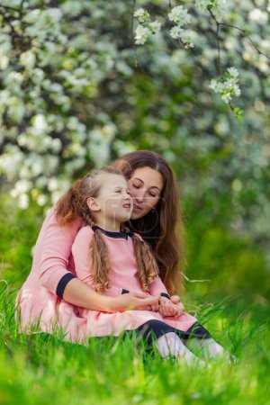 Photo for Mother and daughter walk through a blooming apple orchard - Royalty Free Image