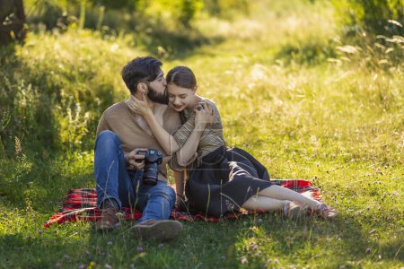 Photo for Young couple sits in nature and looks at the camera at the resulting picture - Royalty Free Image