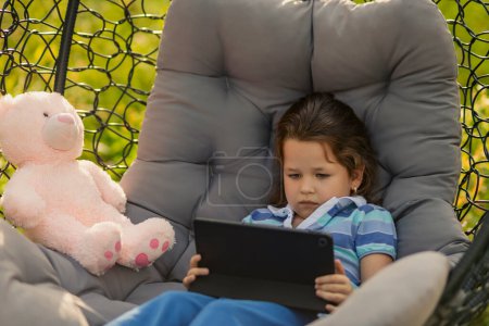 Photo for Little girl looking at tablet, modern outdoor recreation - Royalty Free Image