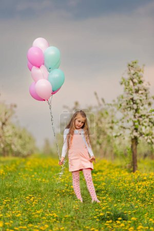Photo for Girl with balloons in a young apple orchard - Royalty Free Image