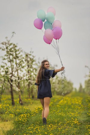 Photo for Girl with balloons in a young blooming garden - Royalty Free Image