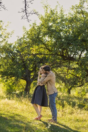 Photo for Young couple, illuminated by the backlit sun, hugging in nature - Royalty Free Image