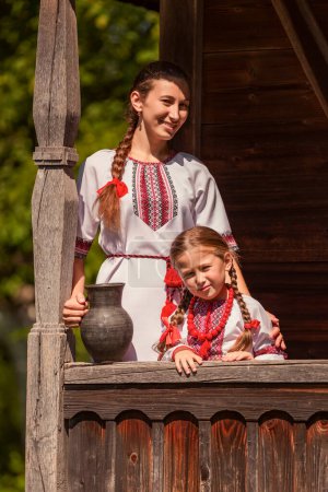 mother and daughter dressed in Ukrainian national costumes look at the camera