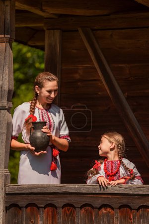 Photo for Mother and daughter dressed in Ukrainian national costumes look at the camera - Royalty Free Image