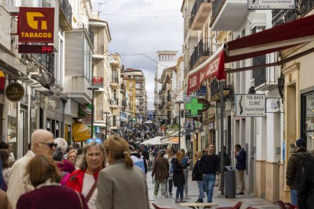 Photo for Ronda, Spain - October 20, 2023: A crowd of many tourists and shoppers, walking on Calle La Bola street in Ronda village, Spain. - Royalty Free Image