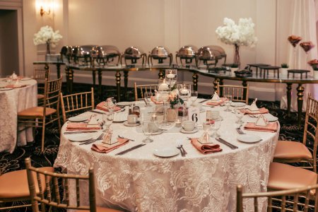 The reserved round table in the restaurant is decorated with flowers and candles. A round table for guests in the restaurant is set for a large company. Table number six