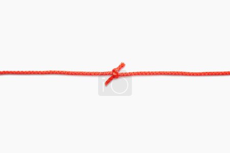 Téléchargez les photos : Les deux extrémités d'une corde rouge sont attachées dans un nœud sur un fond isolé blanc. Corde en nylon rouge avec un nœud au centre. Espace libre pour le texte et la publicité - en image libre de droit