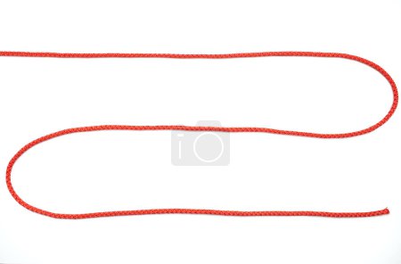 Rotes Seil in Form eines Zickzackes auf weißem, isoliertem Hintergrund. Rotes Nylonseil liegt auf weißem Hintergrund, Draufsicht. Freiraum für Text