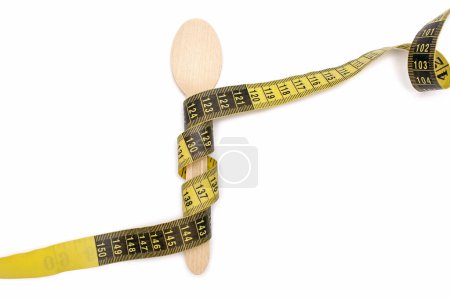 Photo for Wooden spoon and measuring tape on a white isolated background. The concept of diet and weight loss. Proper nutrition and calorie restriction. Yellow measuring tape wrapped around a wooden spoon - Royalty Free Image