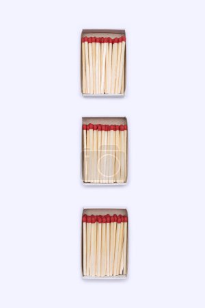 Three open matchboxes filled with matches are vertically arranged on a white background. Top view of matches close-up with space for text. Matchboxes with matches isolated on white background.