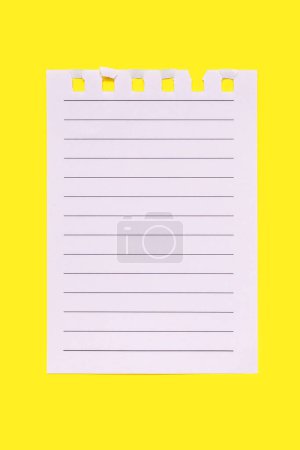 A torn page from a notebook on a yellow vertical background. Notebook paper with black horizontal lines. Lined paper with space for text, note, list. Close-up of one lined paper torn from a notebook