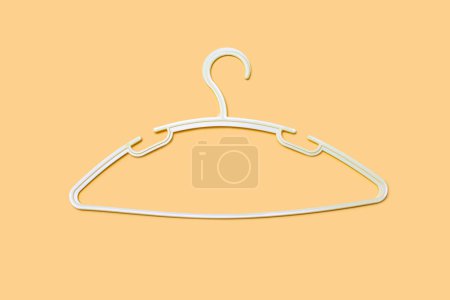 Photo for Empty plastic hanger isolated on orange background close-up. Potential copy space above and inside clothes hangers. A white clothes hanger is empty without clothes. - Royalty Free Image