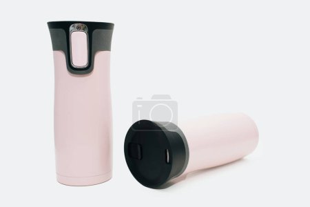 Photo for Two pink reusable water bottles are standing and lying on a white background. Modern pink thermos for tea, coffee or water. Travel thermos for hot drinks, travel bottle, reusable water bottle. - Royalty Free Image