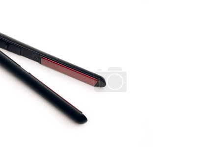 Black hair straightener isolated on white background with free space for text. Electronic hair straightener with ceramic plates. Hair styling tool. The concept of hair care at home