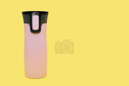 Rosa Thermoskanne für Tee, Kaffee oder Wasser isoliert auf gelbem Hintergrund mit freiem Platz für Text. Geschlossene Reisethermoskanne, Reiseflasche, Getränkebehälter, Mehrwegflasche.