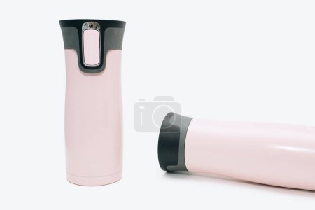Photo for Modern pink metal thermoses for tea, coffee, or water. Two pink reusable water bottles are standing and lying on a white background. Travel thermos for hot drinks, travel bottle, reusable water bottle - Royalty Free Image