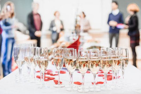 Foto de Evento de banquete. Mesa con las gafas de vino, aperitivos y cócteles. Gente celebrando en el fondo
. - Imagen libre de derechos