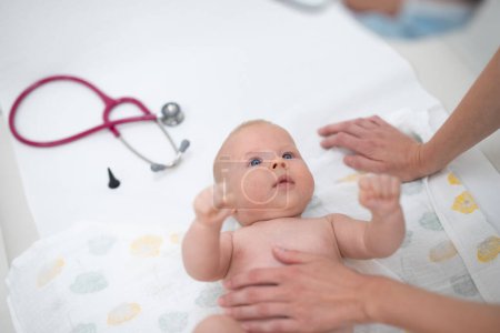 Foto de Bebé acostado boca arriba mientras su médico lo examina durante un chequeo médico estándar
. - Imagen libre de derechos