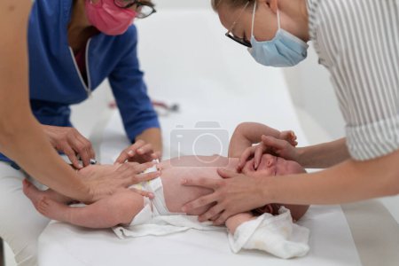 Téléchargez les photos : Bébé beeing vacciné par un pédiatre en présence de sa mère. Vaccination préventive contre la diphtérie, la coqueluche, le tétanos, l'hépatite, l'haemophilus influenzae, le pneumocoque, la poliomyélite. - en image libre de droit
