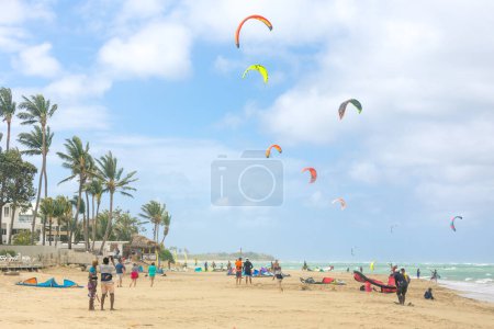 Foto de Multitud de deportistas activos disfrutando de vacaciones de kitesurf y actividades en un día soleado perfecto en la playa de arena tropical de Cabarete en República Dominicana - Imagen libre de derechos