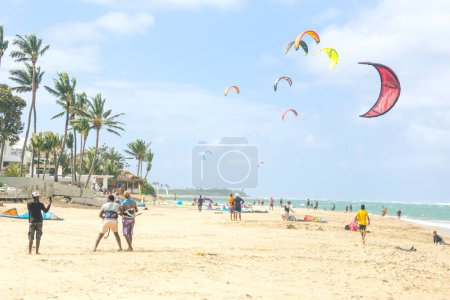 Foto de Multitud de deportistas activos disfrutando de vacaciones de kitesurf y actividades en un día soleado perfecto en la playa de arena tropical de Cabarete en República Dominicana - Imagen libre de derechos