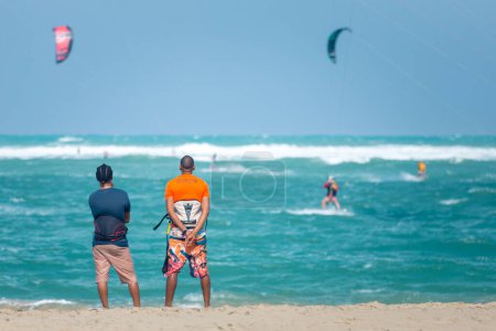 Téléchargez les photos : Des sportifs actifs profitant de vacances de kitesurf et d'activités par une journée ensoleillée parfaite sur la plage de sable tropical de Cabarete en République dominicaine - en image libre de droit