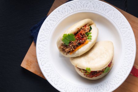 Photo for Food concept Homemade organic Pulled Beef Bao Buns or Gua Bao in white ceramic plate on black background with copy space - Royalty Free Image