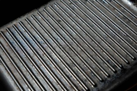 Texture of empty black cast heavy iron grill pan, actively used modern kitchen equipment