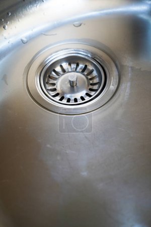 Stainless steel sink and water drain in a modern kitchen, water flow in the kitchen sink, water goes from the drain