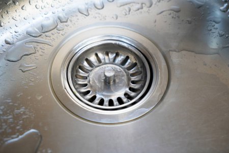 Stainless steel sink and water drain in a modern kitchen, water flow in the kitchen sink, water goes from the drain