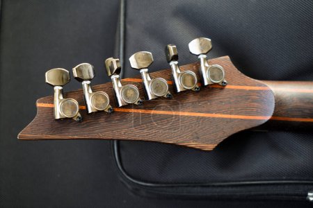 Close-up of electric guitar steel strings headstock and fretboard made of rosewood rest on a plush guard