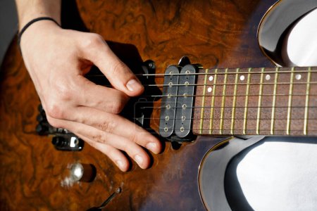 Mains d'un musicien caucasien jouant de la guitare électrique, jouant de la guitare électrique en bois de couleur brun vif