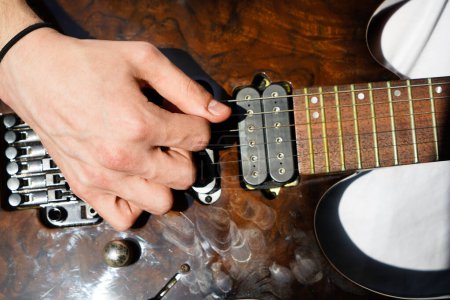 Manos de un músico caucásico tocando la guitarra eléctrica, tocando la guitarra eléctrica de madera de color marrón brillante