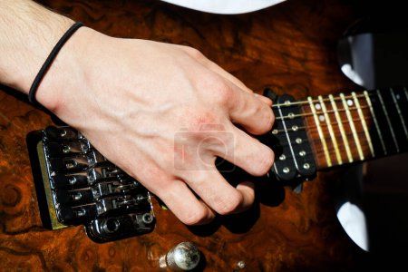 Hände eines kaukasischen Musikers, der E-Gitarre spielt, helles braunes Holz, E-Gitarre