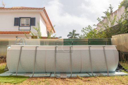 Tranquilo hogar piscina con una escalera de metal, encerrado en un jardín tranquilo patio trasero, entorno diurno.