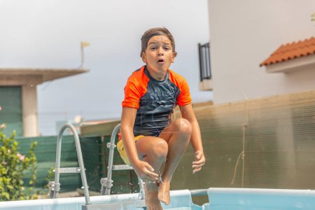 Photo for Joyous boy captured mid-jump over a pool, mouth open wide, expressing sheer excitement on a sunny day - Royalty Free Image