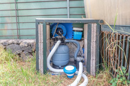 Système de filtration de piscine comprenant la pompe, le filtre et les tuyaux, vital pour l'entretien de la piscine dans une cour arrière de la maison.