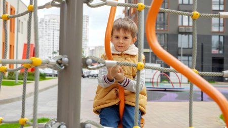 Téléchargez les photos : Joyeux garçon souriant assis sur un manège et tournant. Enfant actif, sport et développement, enfants jouant à l'extérieur - en image libre de droit