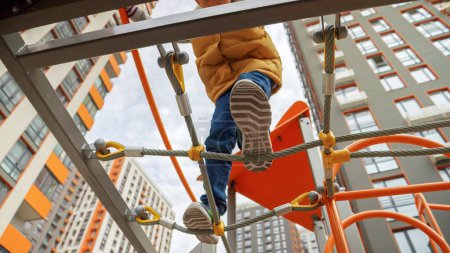 Photo for View from the ground on kid's feet walking over rope bridge or net at playground. - Royalty Free Image