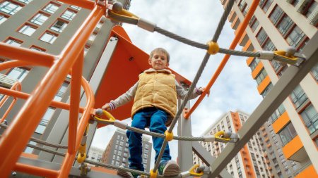 Photo for View from the ground on little boy walking over the rope bridge and nets at playground. Active child, sports and development, kids playing outdoors. - Royalty Free Image