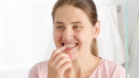 Photo for Portrait of happy smiling woman standing in bathroom and checking her mouth and teeth. Concept of teeth health, self checking mouth and oral hygiene - Royalty Free Image