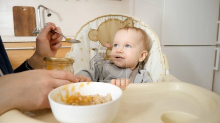 Photo for Portrait of little baby boy getting messy while eating porridge in highchair. Concept of parenting, healthy nutrition and baby feeding - Royalty Free Image