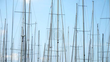 Téléchargez les photos : Beaucoup de mâts de yachts et de navires dans le port sur un ciel bleu clair. - en image libre de droit