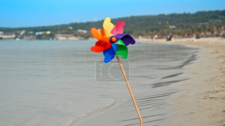 Photo for Pinwheel spins joyfully on a sandy beach, embodying the essence of summer holidays, travel, and beach tourism. - Royalty Free Image